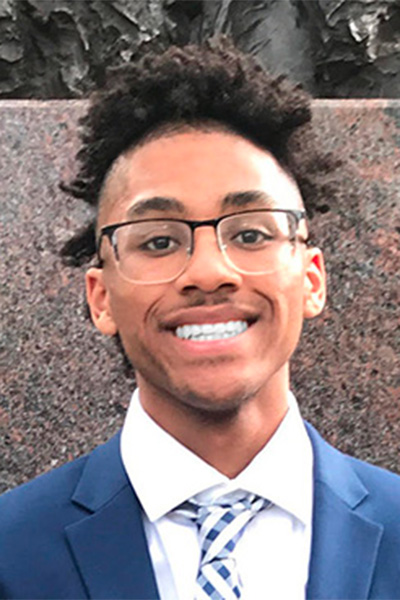 Headshot of Joey Arnold, a young Black man, wearing glasses, a blue suit jacket, and a blue and white plaid tie. He is identified as the 2022 IEEE Scholarship Plus Initiative Scholar, Class of 2022, M.Eng., Electrical & Electronics Engineering, Drexel University College of Engineering. 